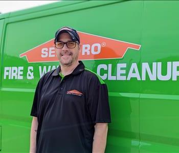 Male standing in front of green SERVPRO truck